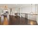 Large open space with dark wood floors, modern light fixture, and wrought iron railings leading to the adjacent dining and kitchen area at 2848 Grand Union Way, Charlotte, NC 28209