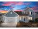 A beautiful two-story home with a two-car garage and inviting front porch illuminated under a captivating sunset sky at 5034 Moselle Ave, Fort Mill, SC 29707