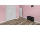 This bedroom features wood-look floors, pink walls, and closet and door to the hallway at 103 Granville Ln, Salisbury, NC 28146