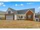 Inviting home exterior with a two-car garage, white siding, brick accents and a cozy front yard fire pit at 103 Granville Ln, Salisbury, NC 28146