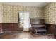 Living room with hardwood floors, antique piano, and patterned wallpaper at 2948 W Main St, Claremont, NC 28610