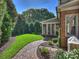 Brick patio pathway, screened porch, lush lawn, and mature trees in the backyard at 6819 Conservatory Ln, Charlotte, NC 28210