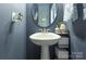 Stylish powder room with pedestal sink and oval mirror at 8119 Merryvale Ln, Charlotte, NC 28214