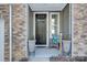 Inviting front porch with stonework, dark door, and potted plants at 8119 Merryvale Ln, Charlotte, NC 28214