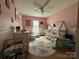 Pink bedroom with wood floors, ceiling fan, cute dino rug, and natural light at 959 Avery Ct, Concord, NC 28025