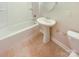 Clean bathroom with pedestal sink, tub and neutral tile floor at 2219 Lochview St, Pineville, NC 28134