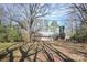 A view of the home's rear exterior with a wooden deck, surrounded by mature trees at 3303 Reid Cir, Monroe, NC 28112