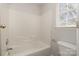 Clean bathroom featuring a bathtub, tile surround, and window at 3821 Bullard St, Charlotte, NC 28208