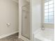 Bright bathroom featuring a glass-enclosed shower, soaking tub, and translucent window for natural light at 5904 Bryant Ln, Waxhaw, NC 28173