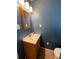 Small blue bathroom with a wooden vanity, mirror, and a standard toilet at 7860 Georgia Ave, Kannapolis, NC 28081