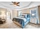 Main bedroom featuring a tray ceiling, ceiling fan, windows, bedside tables, and access to the main bath at 79031 Ridgehaven Rd, Lancaster, SC 29720