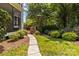 Lush backyard featuring a stone pathway, leading to a brick patio and screened porch, perfect for entertaining at 110 Lynbrook Dr, Davidson, NC 28036