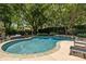 Backyard pool and entertaining space, surrounded by mature trees and greenery, create a private outdoor oasis at 110 Lynbrook Dr, Davidson, NC 28036