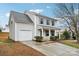 This two-story home boasts light gray siding, a covered front porch, attached one-car garage and well-maintained landscaping at 12218 Stewarts Crossing Dr, Charlotte, NC 28215