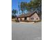 Rustic wooden building with a brown roof, surrounded by trees and featuring ample parking space at 132 Picasso Trl, Mount Holly, NC 28120