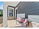 Cozy front porch with decorative pillows on a metal bench, brick accents, and stylish gray siding at 132 Picasso Trl, Mount Holly, NC 28120