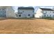 View of backyard and back of house, with an unfinished yard and houses surrounding the property at 1433 Harleston St, Indian Trail, NC 28079