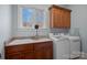 Laundry room with wooden cabinets, washer, dryer, and a large window at 20517 Queensdale Dr, Cornelius, NC 28031