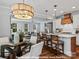 Bright dining area with a round glass table, white chairs, and an elegant light fixture adjoining the kitchen and living room at 272 Gilead Rd, Huntersville, NC 28078