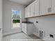 Functional laundry room featuring white cabinetry, a sink, and stylish patterned flooring at 272 Gilead Rd, Huntersville, NC 28078