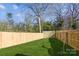 Well-maintained backyard featuring a wood fence, green grass and mature trees at 3132 Carol Ave, Charlotte, NC 28208