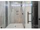 Bathroom shower featuring light gray tiling, glass door, rainfall shower head, and built-in shelves at 529 Veloce Trl, Fort Mill, SC 29715