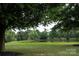 Picturesque view of a tranquil pond surrounded by lush greenery, mature trees, and a charming red barn at 5645 White Store Rd, Wingate, NC 28174