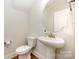 Clean and minimalist powder room with a pedestal sink, round mirror, and modern fixtures at 604 Amalfi Dr, Davidson, NC 28036