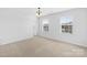 Well-lit bedroom featuring neutral carpet, an entry door, and two windows at 7405 Bosson Sw St, Concord, NC 28025