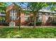 Brick townhome exterior with well-maintained lawn, mature trees and steps leading up to the front door at 128 Steinbeck Way # E, Mooresville, NC 28117