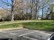 Spacious grassy area with mature trees and a shed in the background, viewed from the parking lot at 16721 Spinnaker Ln, Cornelius, NC 28031