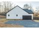 Back exterior view of a home with dark roof, white siding, and a black garage door at 252 Big Lick Rd, Stanfield, NC 28163