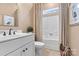 This bathroom features a white sink, toilet, framed mirror, and a shower/bath combination with neutral toned shower curtains at 4998 Looking Glass Trl, Denver, NC 28037
