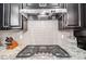 Close-up of a modern stovetop with stainless steel hood, sleek backsplash, and granite countertops at 109 Belfry Loop, Mooresville, NC 28117