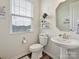 Cozy bathroom with a pedestal sink, decorative mirror, window with blinds, and neutral decor at 114 Marron Dr, Indian Trail, NC 28079