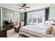 Cozy bedroom featuring a large window, ceiling fan, TV, reading chair, and an adjacent bathroom at 115 Union Chapel Dr, Mooresville, NC 28117