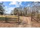 Driveway entrance to a property with wooden fencing and open fields at 11745 Stokes Ferry Rd, Gold Hill, NC 28071