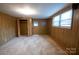 This bedroom features neutral carpet, wood paneled walls, a closet, and a window for natural light at 2905 Maryland Ave, Kannapolis, NC 28083