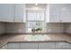 Bright kitchen featuring white cabinets, a double sink, and a garden window at 298 Upper Stanley Rd, Stanley, NC 28164