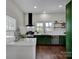 Modern kitchen with dark green cabinets, white countertops, and stainless steel appliances at 301 S Washington St, Monroe, NC 28112