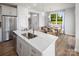 Kitchen island with stainless steel sink, white countertops, and seating, connecting to a dining area at 3038 Finchborough Ct # 234, Charlotte, NC 28269