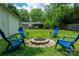 Spacious backyard featuring a fire pit area, blue Adirondack chairs, and lush greenery, with a lawn at 3531 Enfield Rd, Charlotte, NC 28205