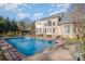 Back of brick home featuring a large pool, patio, and fenced yard under a bright blue sky at 4316 Mourning Dove Dr, Matthews, NC 28104