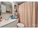 Modern bathroom with a large mirror, chrome fixtures, and a shower with a peach-colored curtain at 5483 Paulmo Dr, Charlotte, NC 28216