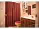 Clean bathroom with a shower/tub combo, wood vanity, and red shower curtain at 5711 Falls Ridge Ln, Charlotte, NC 28269