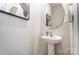 Stylish powder room featuring a pedestal sink, round mirror, and modern wall art at 624 Cassidy Ct, Clover, SC 29710