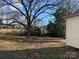 Backyard with large tree and some patchy grass at 907 Sioux St, Monroe, NC 28110