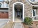 Close-up of a stone-covered front porch with an arch, featuring a seating area and wooden front door at 9730 Briarwick Ln, Charlotte, NC 28277