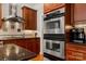 Close-up of the kitchen featuring stainless steel double ovens and a gas cooktop with a range hood at 1016 Antioch Woods Ln # 36, Weddington, NC 28104