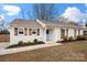 Charming white brick home featuring a light blue door, wood shutters, and manicured landscaping at 11400 Five Cedars Rd, Charlotte, NC 28226